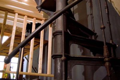 Chambre lumineuse avec lit double, fauteuil en bois, baignoire blanche et grande fenêtre donnant sur l'extérieur.