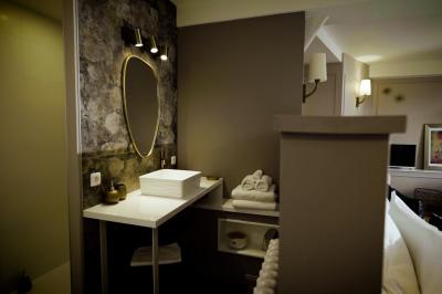 Chambre lumineuse avec lit double, fauteuil en bois, baignoire blanche et grande fenêtre donnant sur l'extérieur.