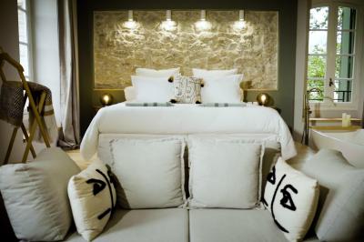 Chambre lumineuse avec lit double, fauteuil en bois, baignoire blanche et grande fenêtre donnant sur l'extérieur.