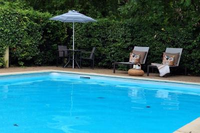 Chambre lumineuse avec lit double, fauteuil en bois, baignoire blanche et grande fenêtre donnant sur l'extérieur.