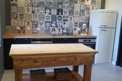 Chambre lumineuse avec lit double, fauteuil en bois, baignoire blanche et grande fenêtre donnant sur l'extérieur.