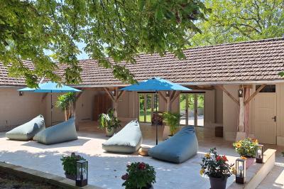 Chambre lumineuse avec lit double, fauteuil en bois, baignoire blanche et grande fenêtre donnant sur l'extérieur.