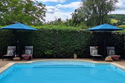 Chambre lumineuse avec lit double, fauteuil en bois, baignoire blanche et grande fenêtre donnant sur l'extérieur.