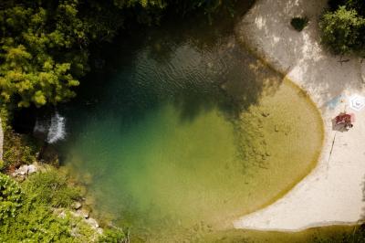 Chambre lumineuse avec lit double, fauteuil en bois, baignoire blanche et grande fenêtre donnant sur l'extérieur.