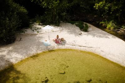 Chambre lumineuse avec lit double, fauteuil en bois, baignoire blanche et grande fenêtre donnant sur l'extérieur.