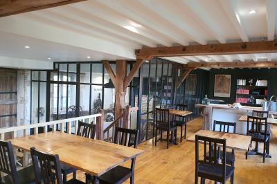 Chambre lumineuse avec lit double, fauteuil en bois, baignoire blanche et grande fenêtre donnant sur l'extérieur.