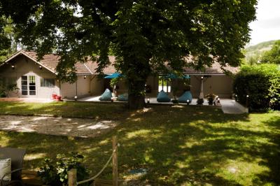 Chambre lumineuse avec lit double, fauteuil en bois, baignoire blanche et grande fenêtre donnant sur l'extérieur.