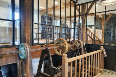 Chambre lumineuse avec lit double, fauteuil en bois, baignoire blanche et grande fenêtre donnant sur l'extérieur.