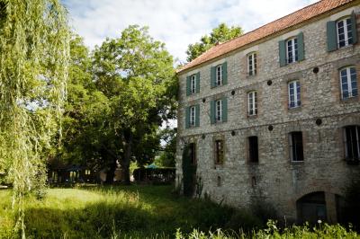 Chambre lumineuse avec lit double, fauteuil en bois, baignoire blanche et grande fenêtre donnant sur l'extérieur.