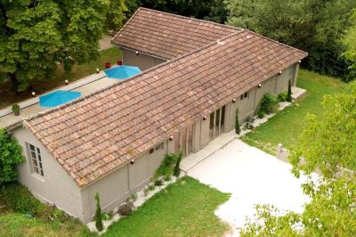 Chambre lumineuse avec lit double, fauteuil en bois, baignoire blanche et grande fenêtre donnant sur l'extérieur.