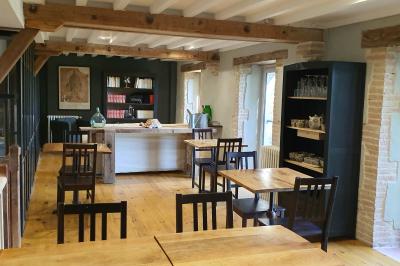 Chambre lumineuse avec lit double, fauteuil en bois, baignoire blanche et grande fenêtre donnant sur l'extérieur.