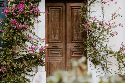 Façade d'une maison provençale jaune à volets verts, éclairée par le soleil couchant, avec une cour pavée et des plantes.