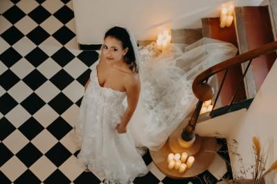 Façade d'une maison provençale jaune à volets verts, éclairée par le soleil couchant, avec une cour pavée et des plantes.