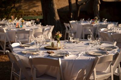 Façade d'une maison provençale jaune à volets verts, éclairée par le soleil couchant, avec une cour pavée et des plantes.