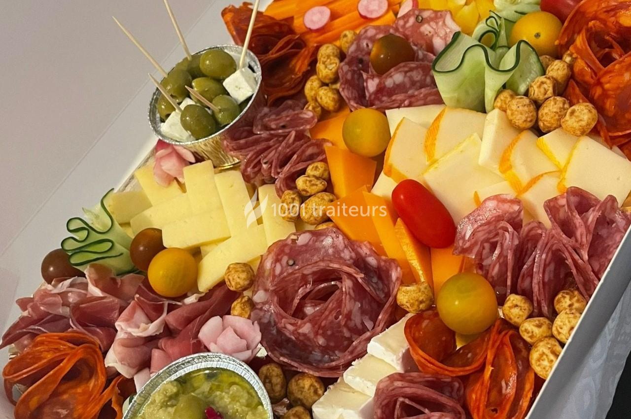 Plateau de charcuterie et fromages avec olives, légumes frais, tomates cerises et condiments variés.