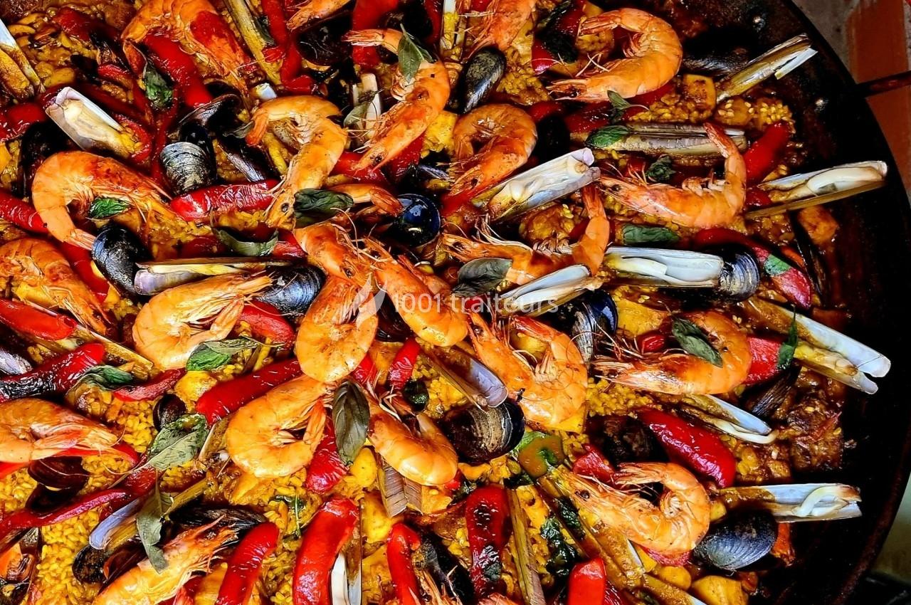Plat de paella colorée avec crevettes, moules, poivrons rouges et riz safrané.