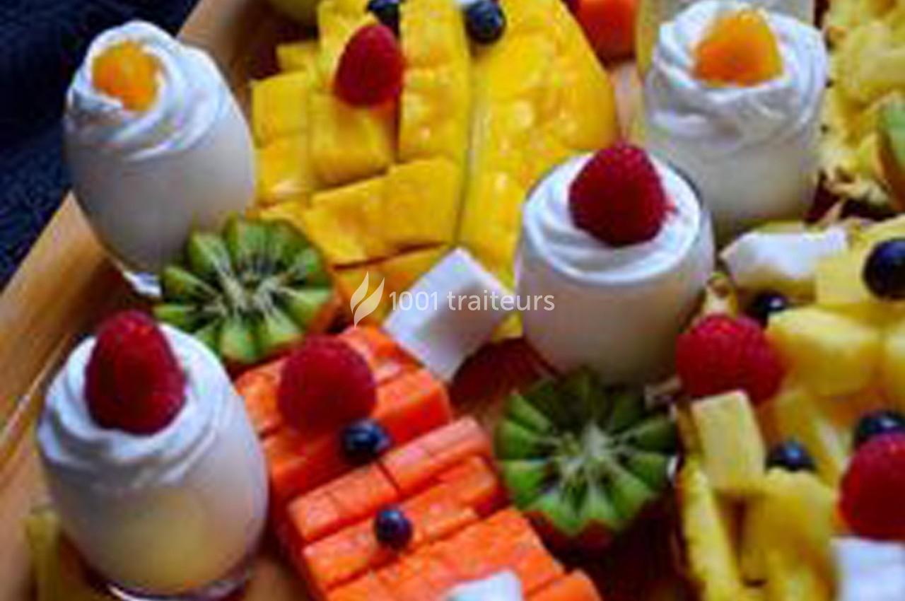 Plateau de fruits variés avec mangue, kiwi, ananas, papaye, et desserts garnis de chantilly et fruits rouges.