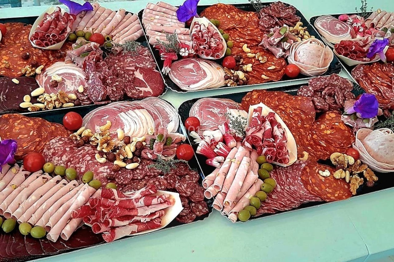 Plateaux de charcuterie variée avec jambon, saucisson, olives, noix et décoration florale.