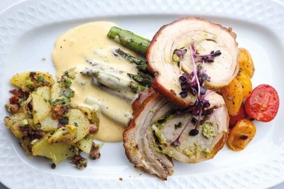 Un couteau s'apprête à couper un dessert en forme de citron posé sur un support doré.