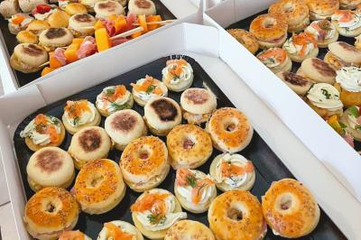 Plateaux garnis de mini-bagels, muffins et amuse-bouches variés, présentés dans des boîtes ouvertes.