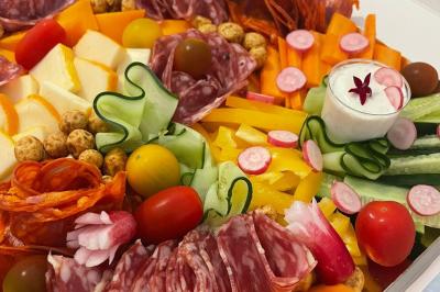 Plat de tajine en terre cuite contenant un mélange de légumes, olives et viande, avec théière et couscous en arrière-plan.