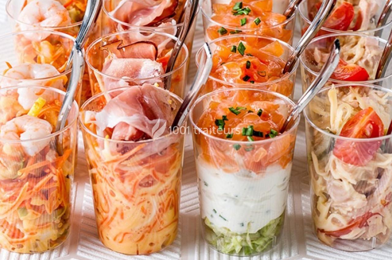 Assortiment de verrines colorées contenant des ingrédients variés comme crevettes, saumon, jambon et légumes.