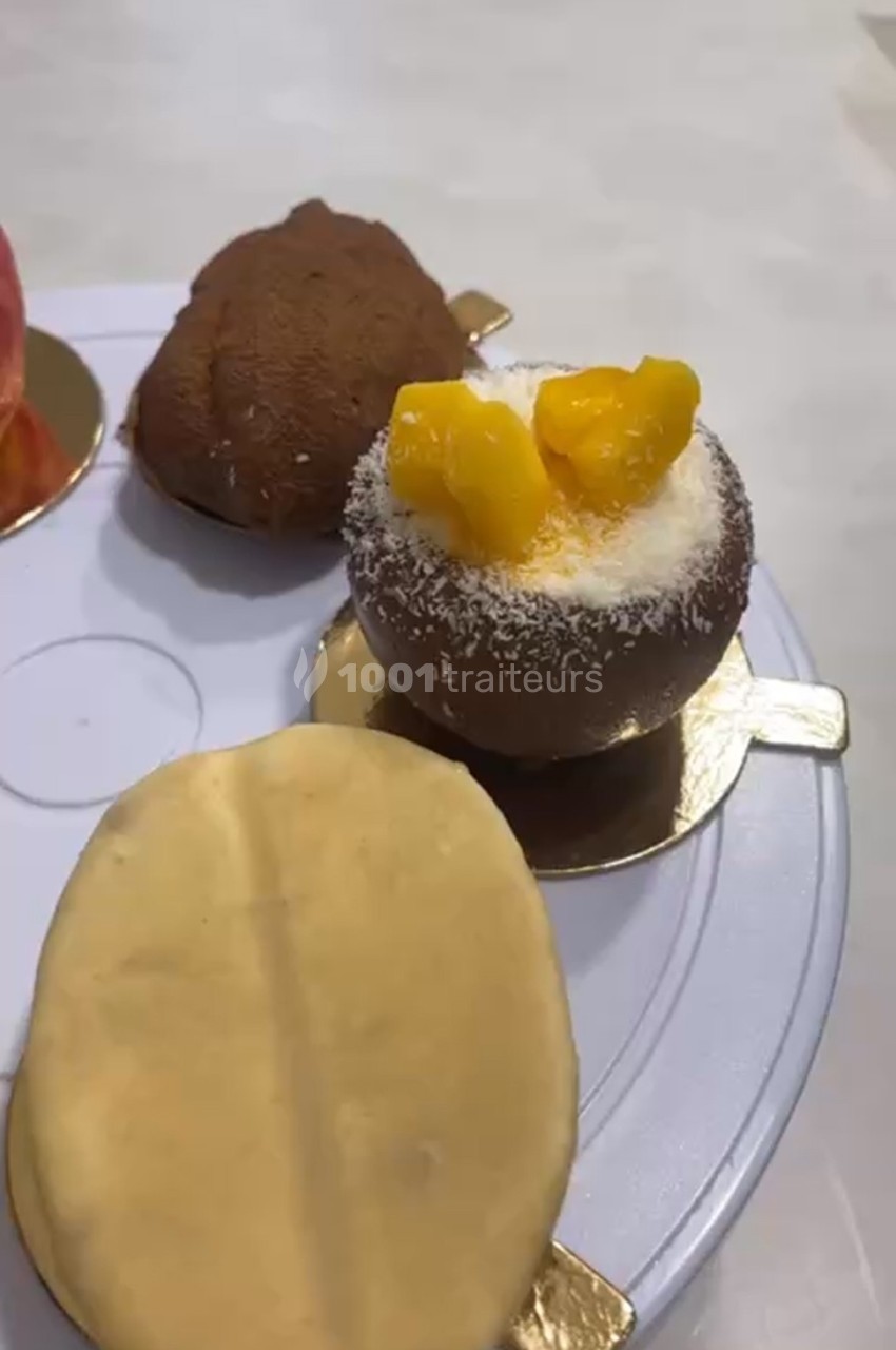 Desserts variés sur un plateau, incluant une pâtisserie garnie de morceaux de fruits et saupoudrée de noix de coco.