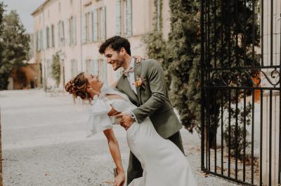 Salle lumineuse avec poutres apparentes, tables blanches disposées en U et chaises rouges, éclairée par des lustres et des…