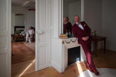 Salle lumineuse avec poutres apparentes, tables blanches disposées en U et chaises rouges, éclairée par des lustres et des…