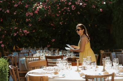 Salle lumineuse avec poutres apparentes, tables blanches disposées en U et chaises rouges, éclairée par des lustres et des…