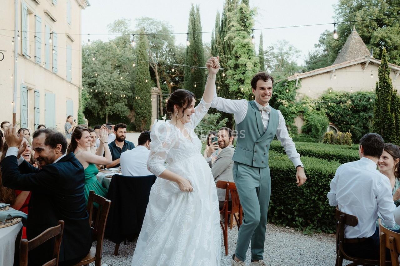 Un couple danse en extérieur lors d'une réception, entouré d'invités assis à des tables décorées.