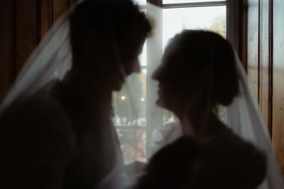 Salle lumineuse avec poutres apparentes, tables blanches disposées en U et chaises rouges, éclairée par des lustres et des…