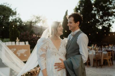 Salle lumineuse avec poutres apparentes, tables blanches disposées en U et chaises rouges, éclairée par des lustres et des…