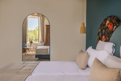 Salle lumineuse avec poutres apparentes, tables blanches disposées en U et chaises rouges, éclairée par des lustres et des…