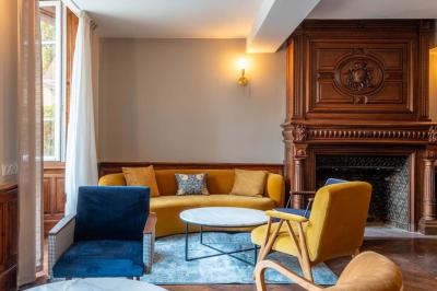 Salle lumineuse avec poutres apparentes, tables blanches disposées en U et chaises rouges, éclairée par des lustres et des…