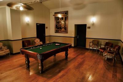 Salle lumineuse avec poutres apparentes, tables blanches disposées en U et chaises rouges, éclairée par des lustres et des…