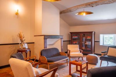 Salle lumineuse avec poutres apparentes, tables blanches disposées en U et chaises rouges, éclairée par des lustres et des…