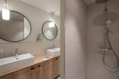 Salle lumineuse avec poutres apparentes, tables blanches disposées en U et chaises rouges, éclairée par des lustres et des…