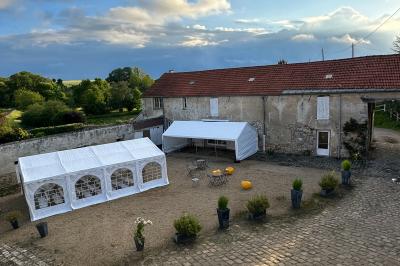Façade d'un bâtiment ancien avec porte vitrée ouverte sur une salle aménagée, table dressée à l'extérieur.