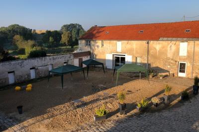 Façade d'un bâtiment ancien avec porte vitrée ouverte sur une salle aménagée, table dressée à l'extérieur.
