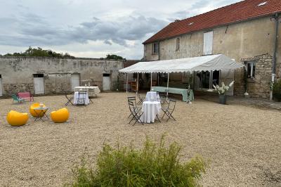 Façade d'un bâtiment ancien avec porte vitrée ouverte sur une salle aménagée, table dressée à l'extérieur.