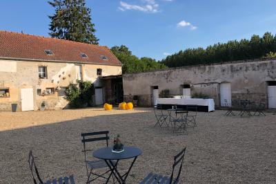Façade d'un bâtiment ancien avec porte vitrée ouverte sur une salle aménagée, table dressée à l'extérieur.