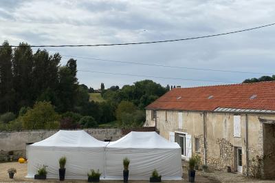 Façade d'un bâtiment ancien avec porte vitrée ouverte sur une salle aménagée, table dressée à l'extérieur.