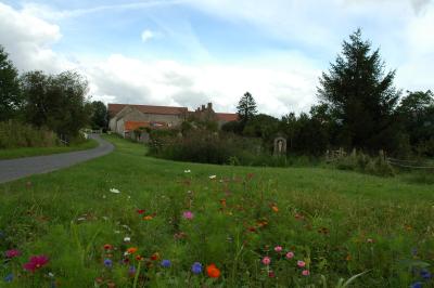 Façade d'un bâtiment ancien avec porte vitrée ouverte sur une salle aménagée, table dressée à l'extérieur.