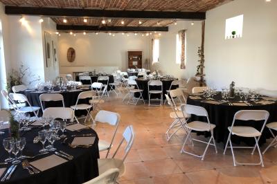 Façade d'un bâtiment ancien avec porte vitrée ouverte sur une salle aménagée, table dressée à l'extérieur.