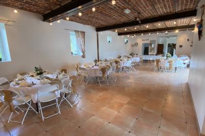 Façade d'un bâtiment ancien avec porte vitrée ouverte sur une salle aménagée, table dressée à l'extérieur.