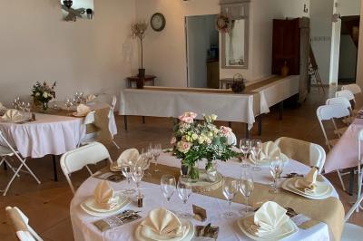 Façade d'un bâtiment ancien avec porte vitrée ouverte sur une salle aménagée, table dressée à l'extérieur.
