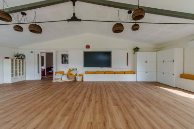 Jardin verdoyant avec fleurs sauvages, arbres et arbustes, entouré d'une clôture en bois sous un ciel dégagé.