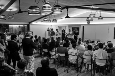 Jardin verdoyant avec fleurs sauvages, arbres et arbustes, entouré d'une clôture en bois sous un ciel dégagé.