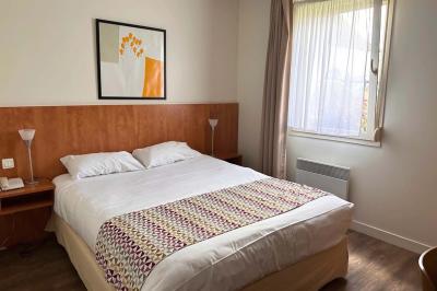 Comptoir en bois avec étagères contenant des bouteilles, tasses, objets décoratifs et plantes dans un espace lumineux.